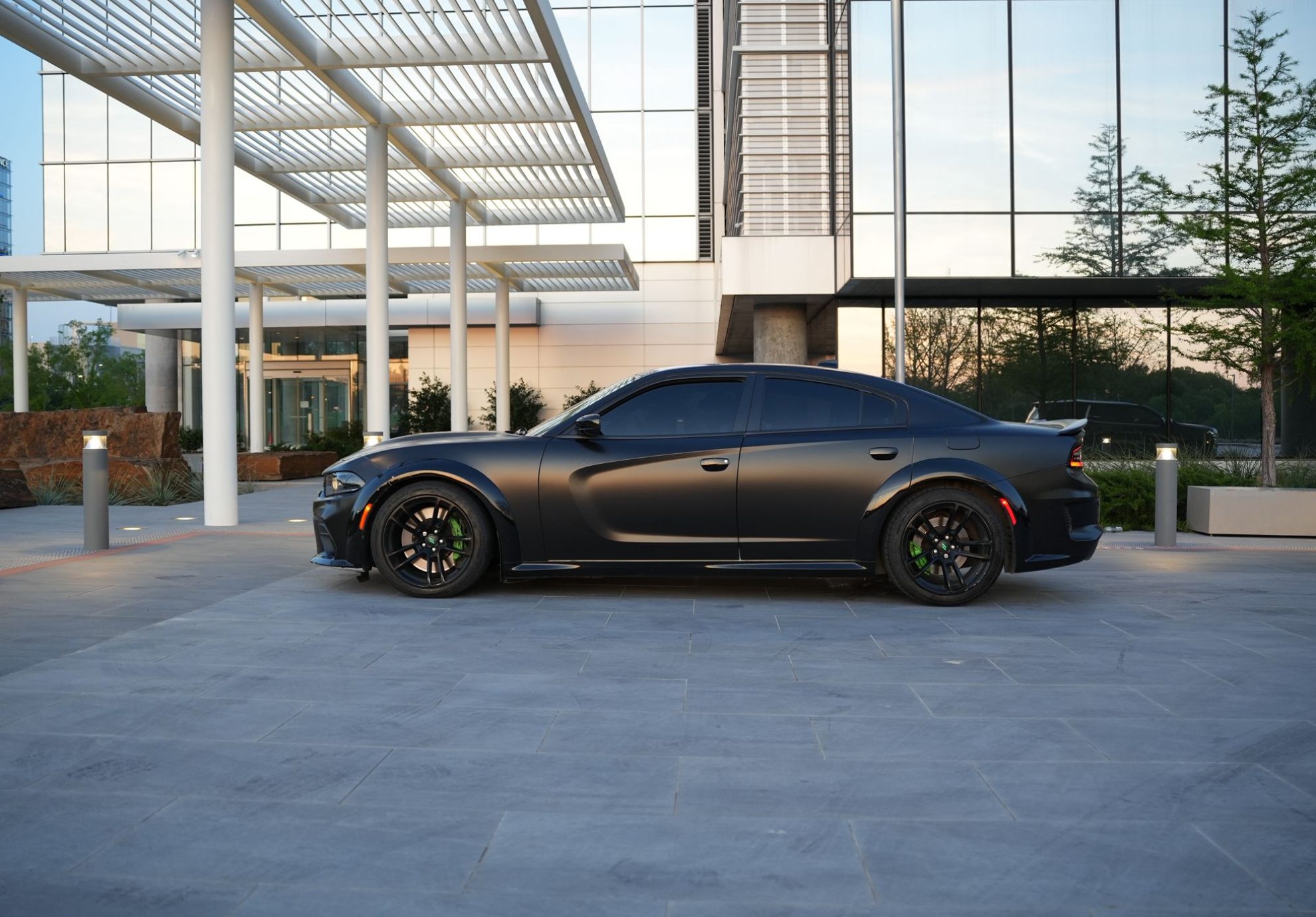 Front view of Dodge Charger Scat Pack Rental in Dallas parked in front of modern building during sunset