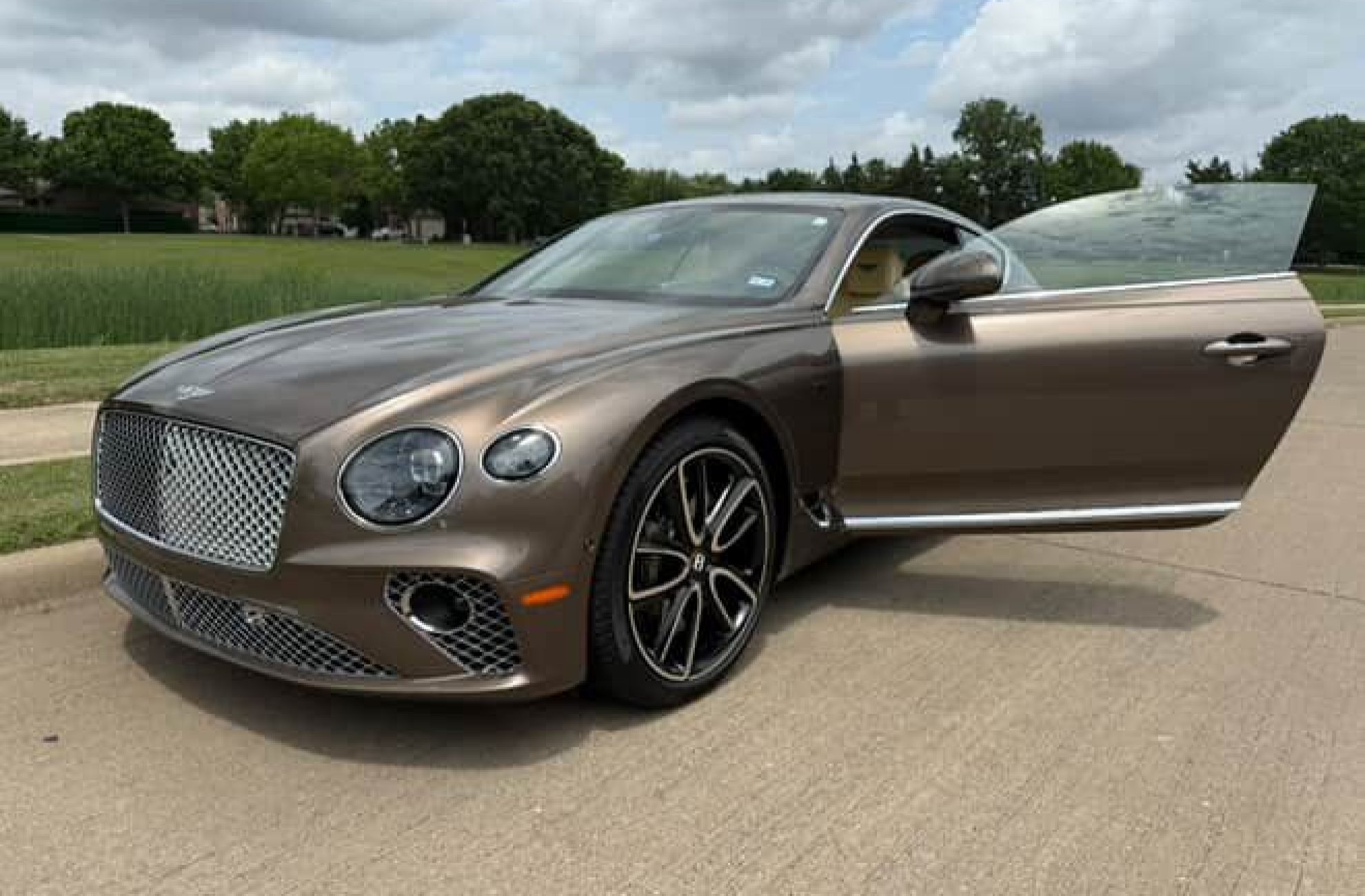 Bentley GT parked in Dallas with the driver door open for a luxury rental experience